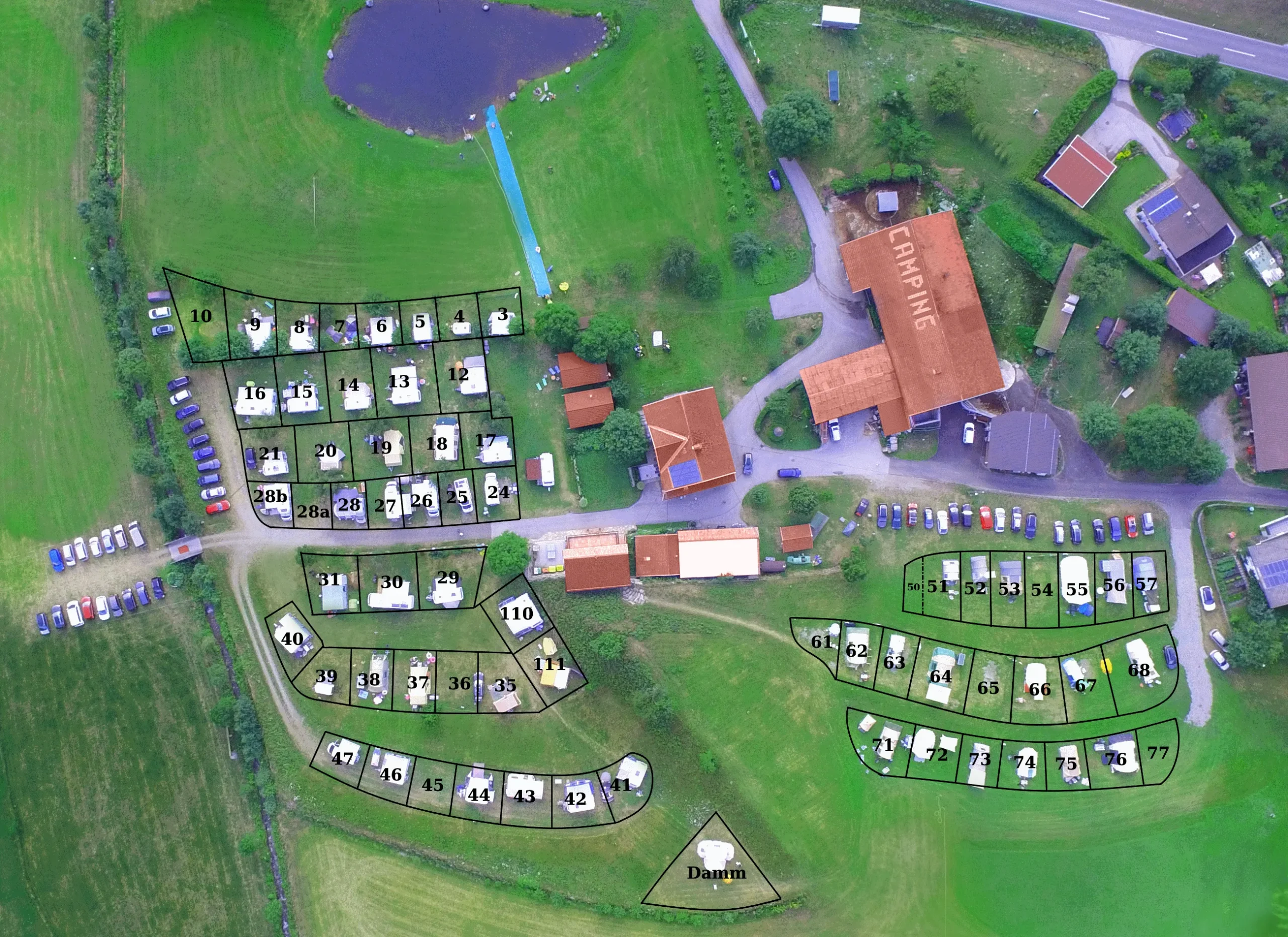 Camping Lindlerhof | Luftaufnahme des Campingplatzes Mölltal Kärnten mit nummerierten Parzellen und einem Teich an der Spitze. Parkplätze sind sichtbar, zusammen mit mehreren Gebäuden mit der Aufschrift „Camping“. Grasflächen und Straßen umgeben dieses idyllische Urlaubsziel, perfekt für Naturliebhaber, die Ruhe suchen.